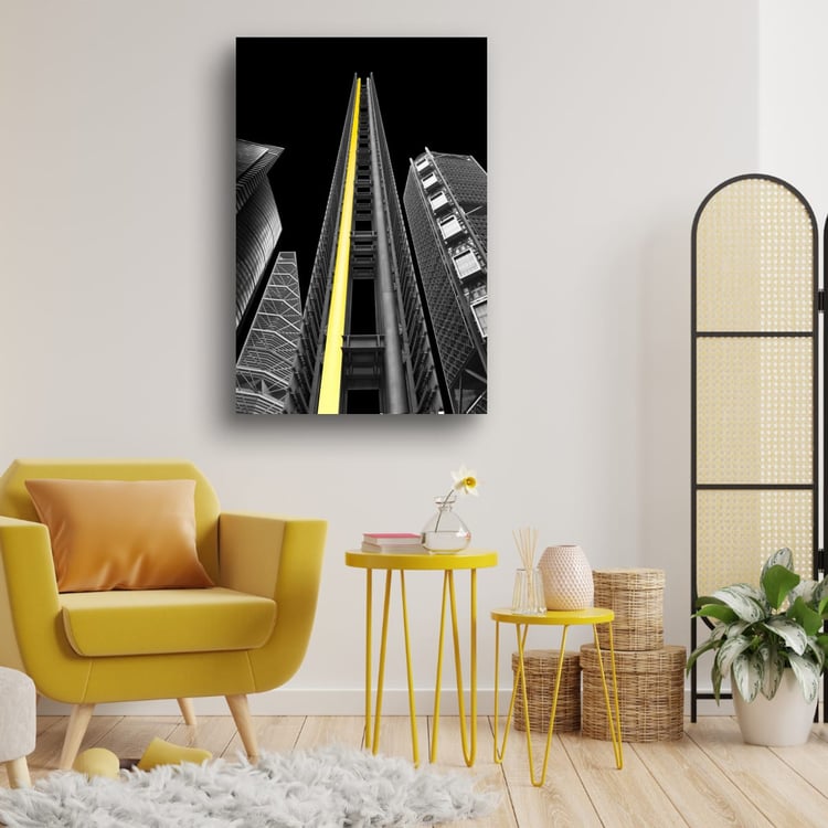 A vertical, high-contrast architectural photograph of steel skyscrapers against a solid black background, featuring a single prominent vertical beam of bright yellow light.