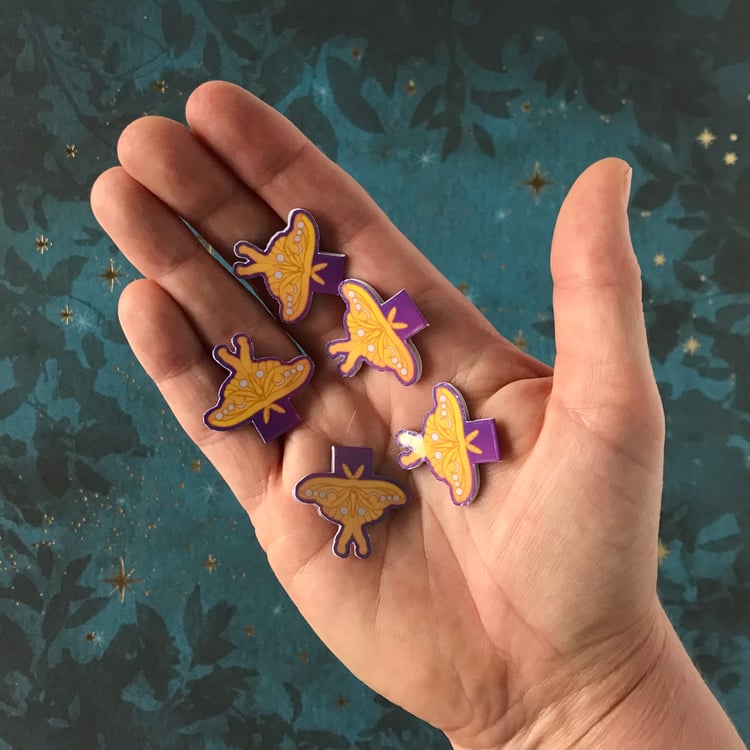 Five mini magnetic bookmarks in a luna moth design shown in-hand to demonstrate their size.