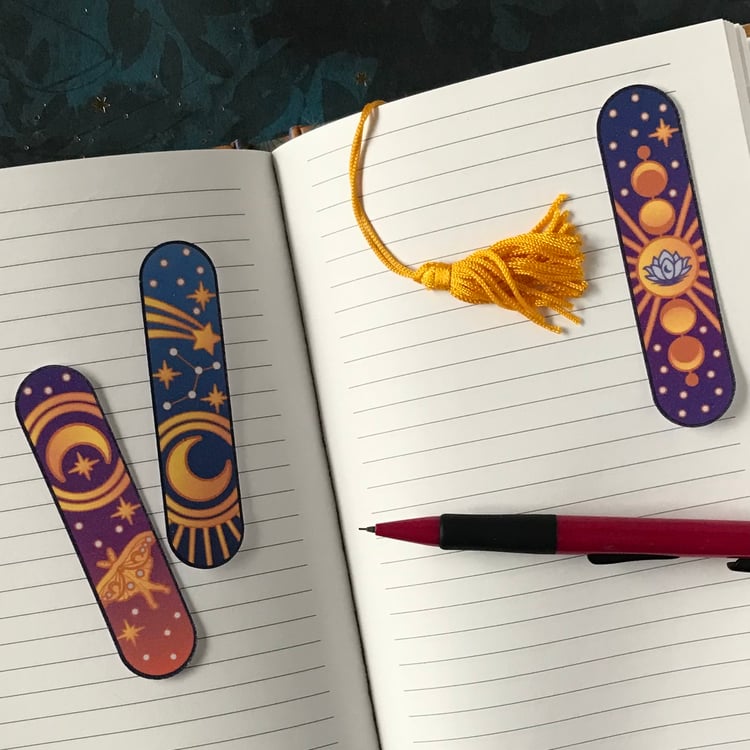 A set of three, sparkly celestial-themed vinyl stickers laid out on a personal journal.