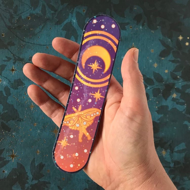 A luna moth and moon celestial-themed decal shown in-hand for scale.