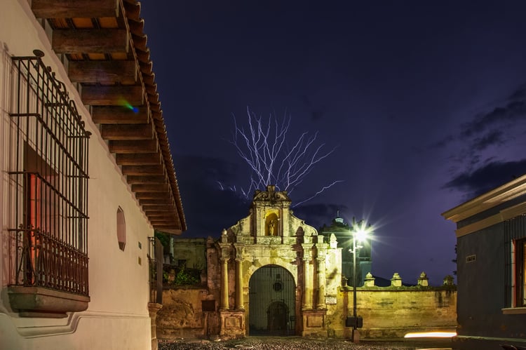 Fine art color night photograph of an electric lightning strike over a colonial stone archway in Antigua, Guatemala by Tony Reddington