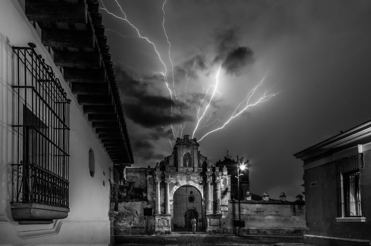 Monochrome fine art print of a dramatic lightning strike over a colonial stone archway in Antigua, Guatemala by Tony Reddington.
