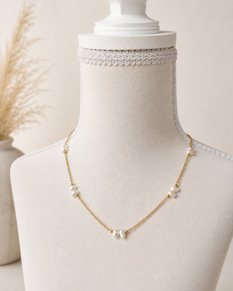 Collana minimal in acciaio color oro con perle di fiume naturali su manichino.