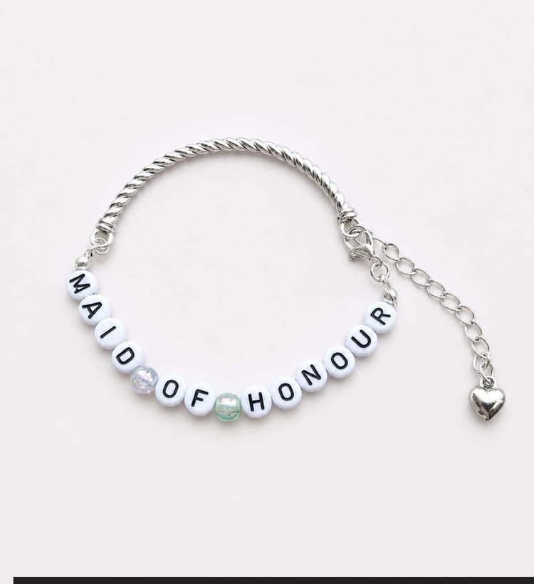 Handmade Maid of Honour bracelet featuring a silver twisted cable bangle, subtle mint green crackle glass spacer beads, white and black MAID OF HONOUR letter beads, and a dangling silver heart charm.