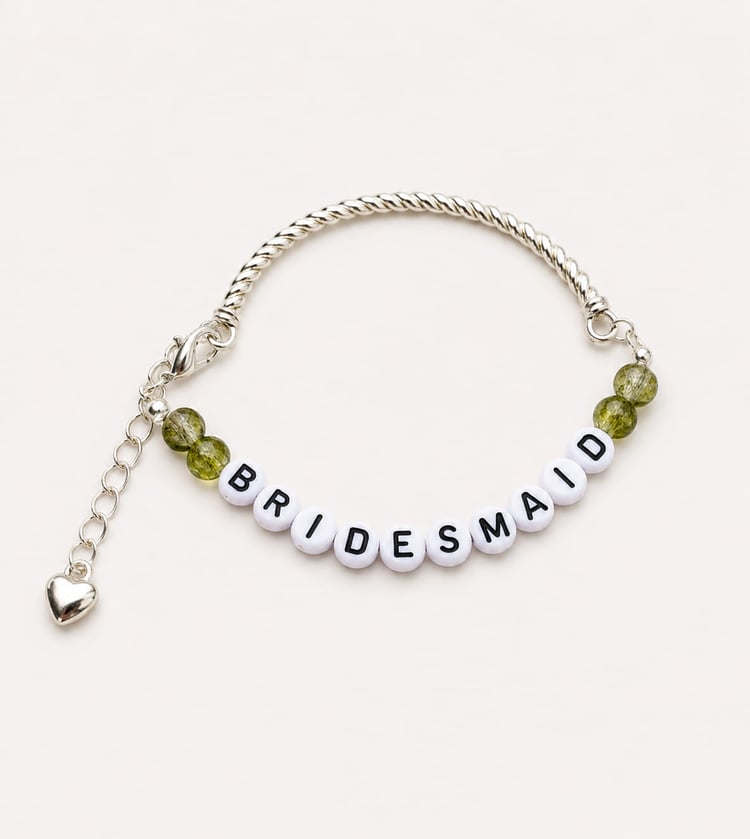 Handmade bridesmaid charm bracelet featuring a silver twisted bangle, olive green crackle glass beads, white and black BRIDESMAID letter beads, and a dangling silver heart charm.