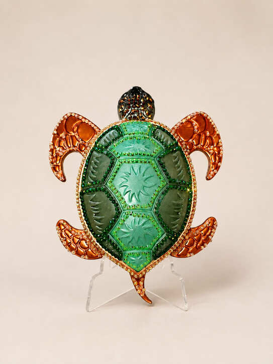 Sparkling resin sea turtle ornament with green translucent shell and bronze-orange flippers displayed upright