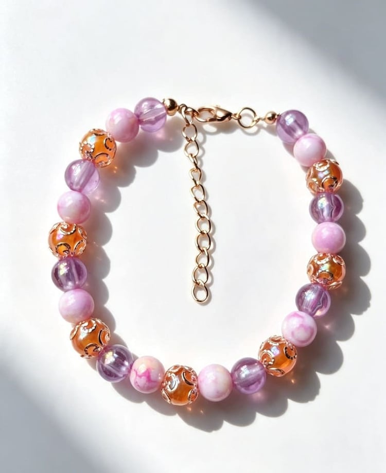 Close-up view of the Violetta beaded bracelet showcasing a detailed pattern of purple, marbled pink, and gold filigree-capped beads with an adjustable extender chain.