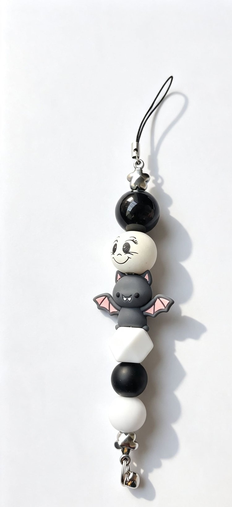 Handmade pastel bat phone charm with grey and pink bat, black and white beads, smiley face bead and black cord loop