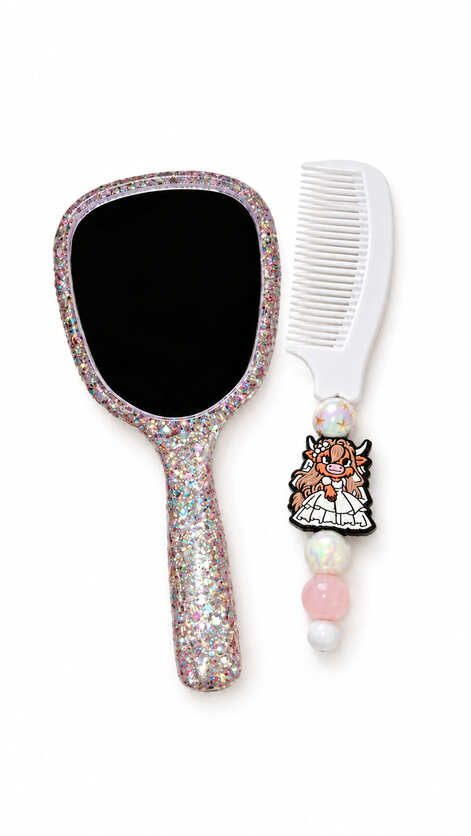 Handmade Highland Glamour Bridal vanity gift set by Sparkling Resin Delights, showing a glittering hand mirror and a white beaded comb. The front of the handheld mirror features a large reflective glass panel bordered in a dense, shimmering pink and silve