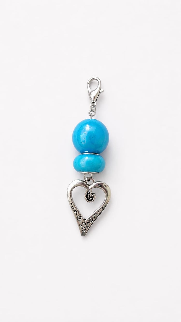 Handmade Something Blue bridal bouquet charm featuring a large, glossy turquoise-blue sphere bead stacked with a smooth, smaller matching turquoise disc bead. Suspended from a silver lobster clasp and finished with a dangling antique-silver open love hear