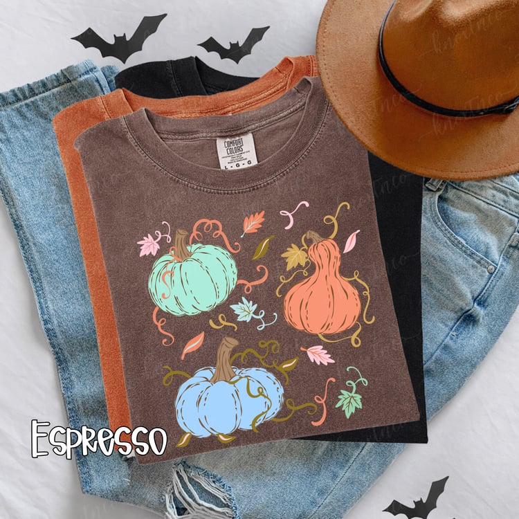 Espresso Comfort Colors T-shirt featuring three colorful whimsical pastel pretty pumpkins in mint green, peach, and light blue with fall leaves and curly vines, styled for autumn and pumpkin season.