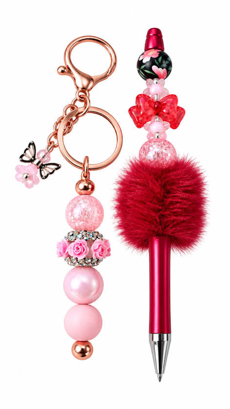 A luxury stationery set containing a rose gold keychain with pink rhinestone rose beads and a matching metallic pink pen adorned with a crimson pom-pom, a translucent red bow, and floral beads.