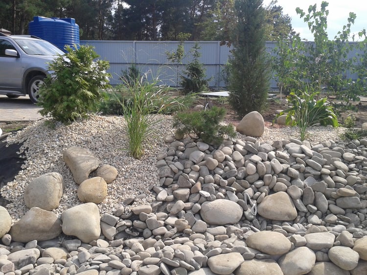 Natural swimming pond construction showing shoreline landform modelling, slope stabilisation, stone finishing and preparation of planted earth mounds in a large private garden.