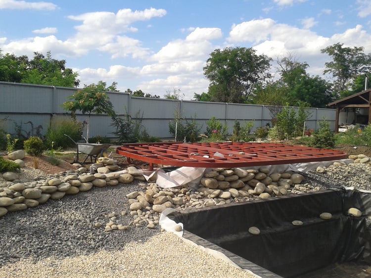 Natural swimming pond construction stages showing the deck framework, shallow regeneration zone, filled pond and completed landscaped water feature in a private garden.