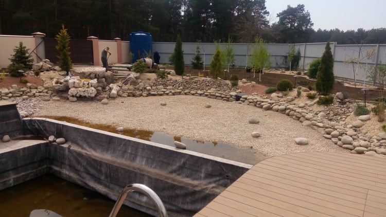 Natural swimming pond construction stages showing the deck framework, shallow regeneration zone, filled pond and completed landscaped water feature in a private garden.