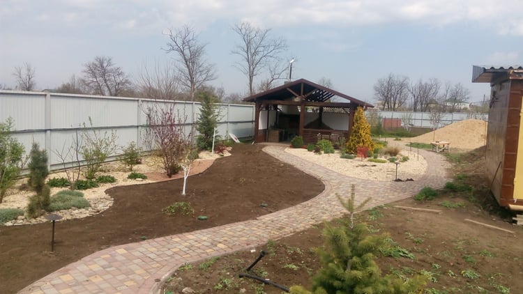 Young private garden during establishment, showing new planting beds, paths and gazebo before the lawn and vegetation fully matured.
