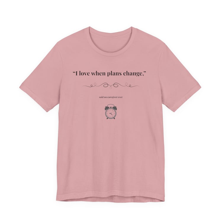Orchid shirt flat lay – “I Love When Plans Change” caregiver design