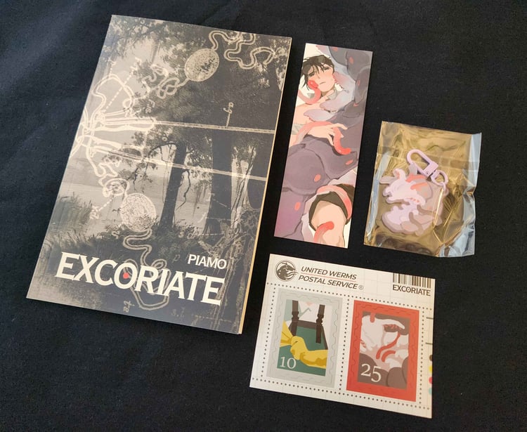 a photograph of a book, a bookmark, stickers, and an acrylic charm