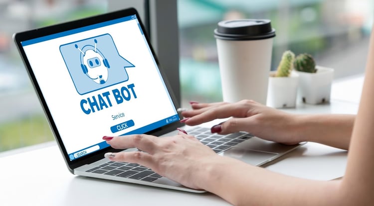 stock photo of a desk surface by a window. Cacti and disposable coffee cup off to the side. Centered is an open laptop with what appears to be a woman's manicured hands ready to type. On the screen is the launch screen for a generic chat bot.