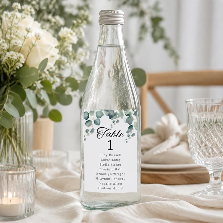 Editable eucalyptus wedding table seating bottle label template featuring watercolor greenery, table numbers and guest names. Includes one 4 by 6 inch rectangular label and a US Letter printing layout with two labels per page for DIY wedding reception déc