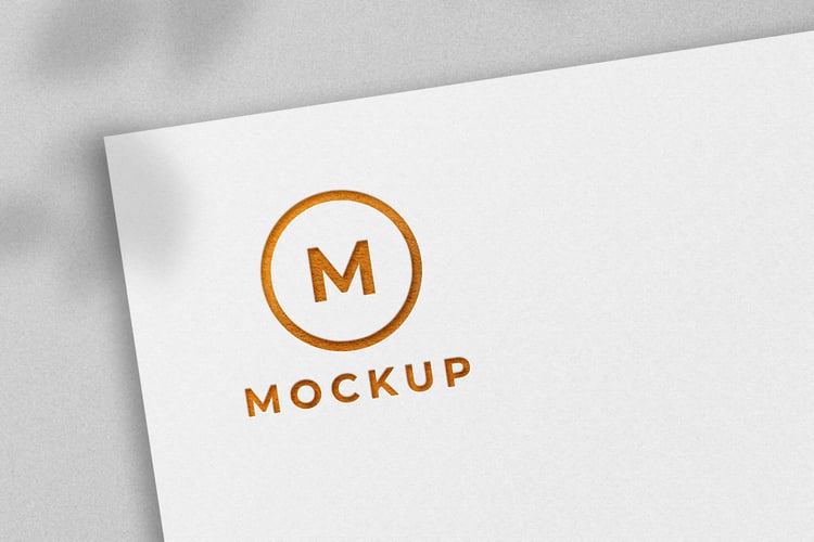 Golden logo mockup embossed on white paper with natural shadow from graphicsregion