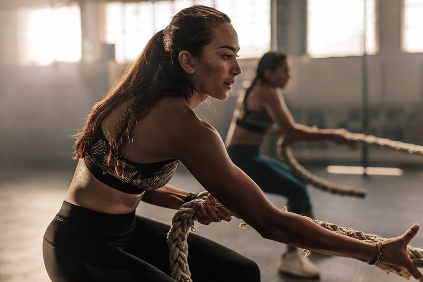 Two (2) Women training hard, pulling heavy rope, motivated and sweaty