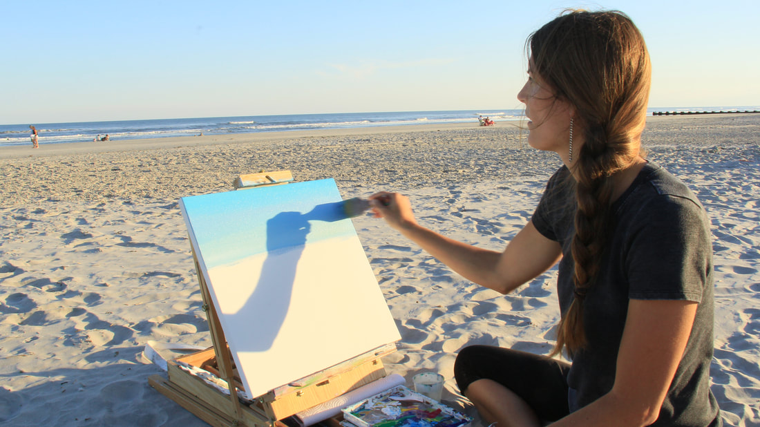 artist bleding colors while painting on the beach