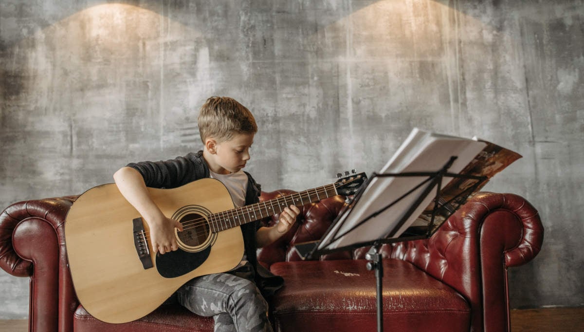 boy playing from a guitar method book