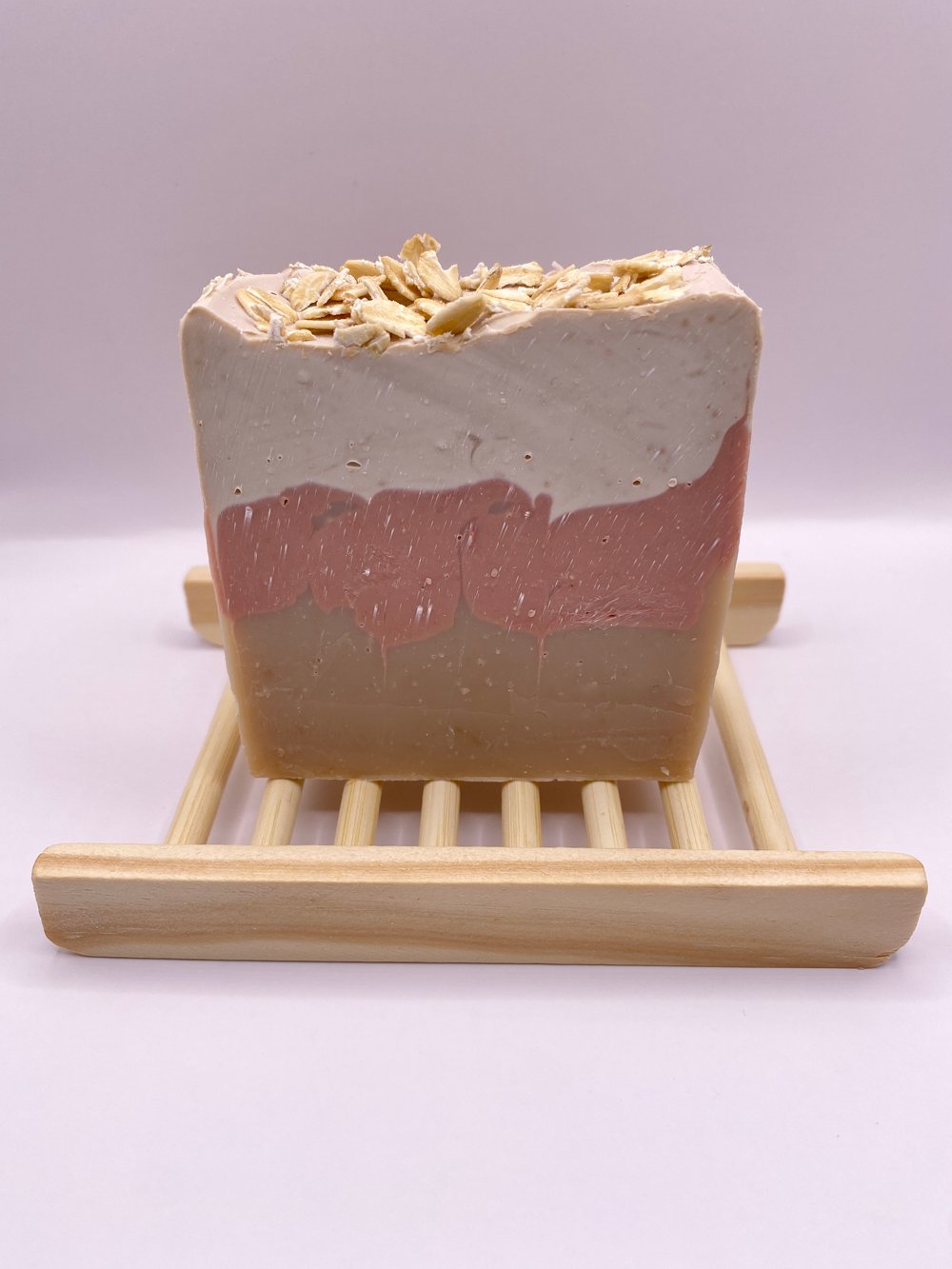 Bar of handmade soap sitting on top of a bamboo bar rack
