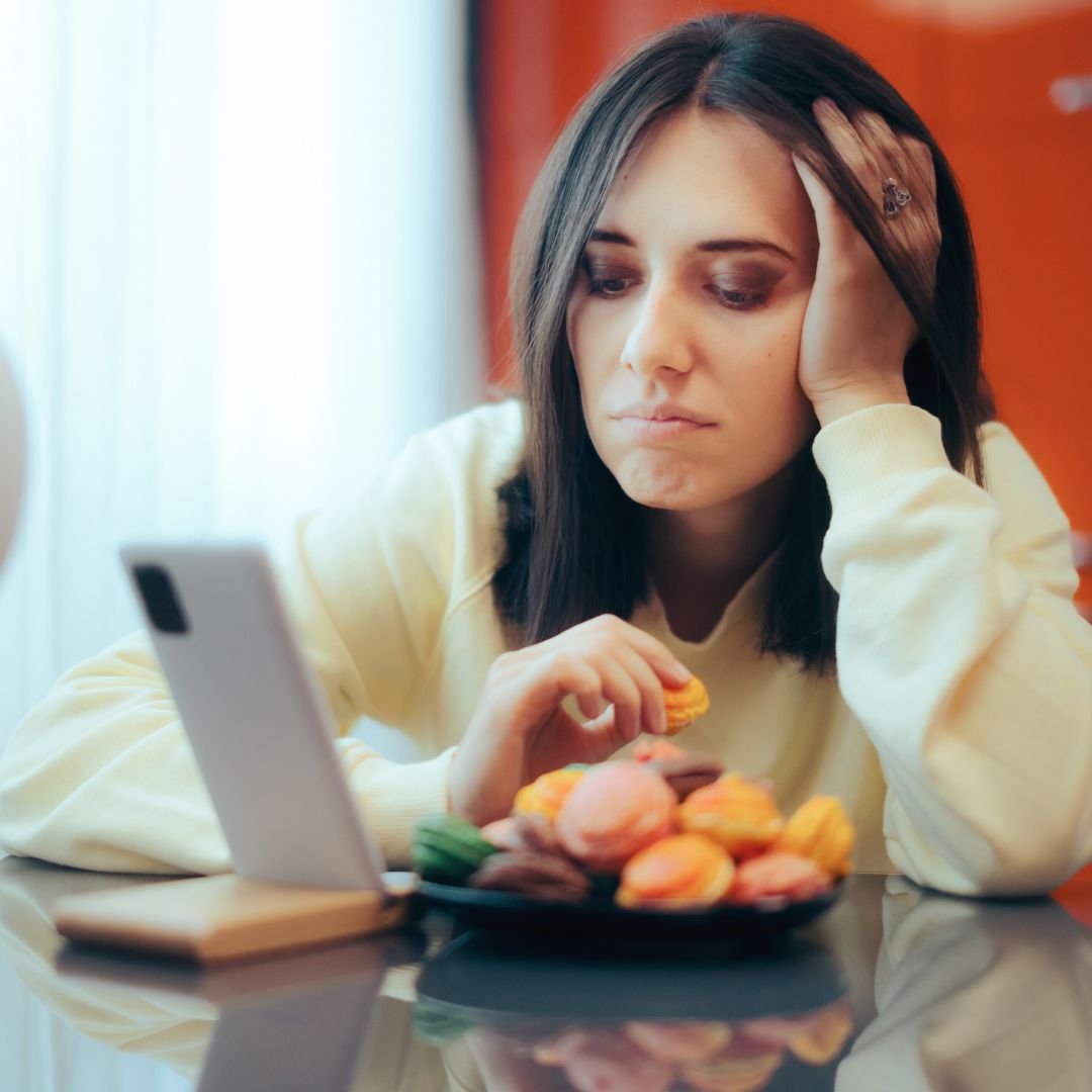 Stressed woman reaching for comfort food as a way of emotional eating.