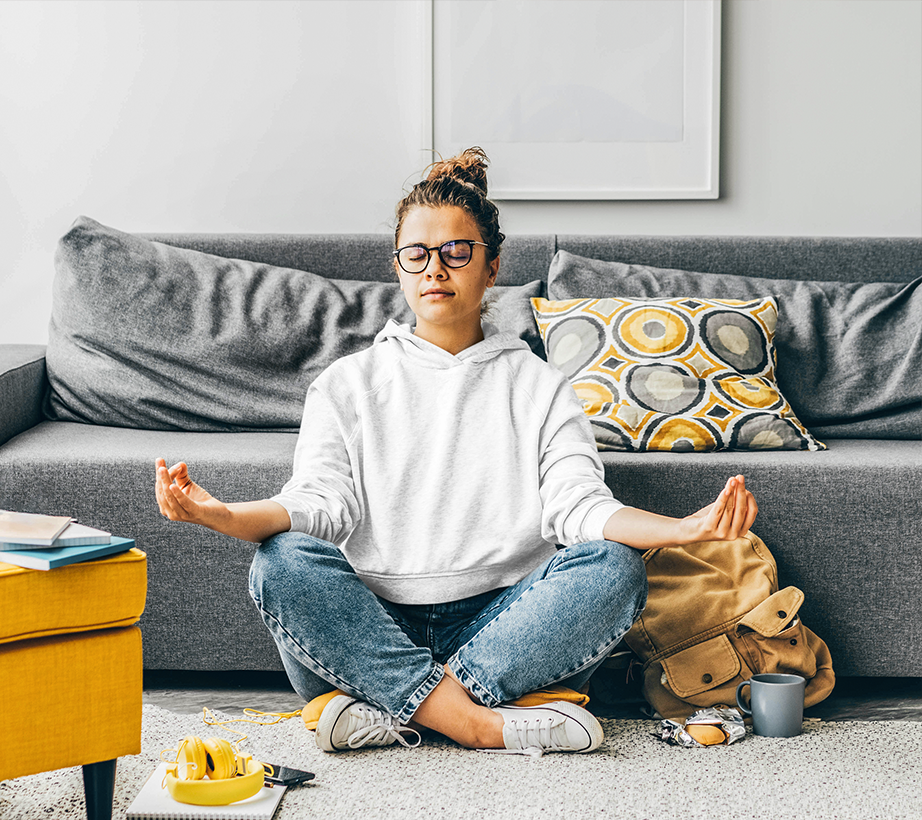 young woman sitting on the floor in front of a couch meditating