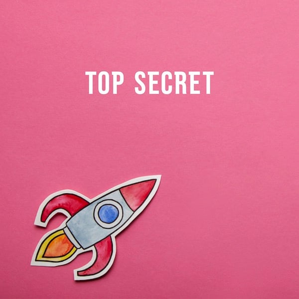 A paper spaceship against a background of pink construction paper. Text reads: top secret