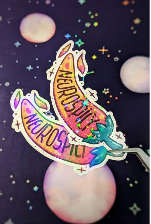 Two colorful peppers with the word "Neurospicy" written on them make up this holographic sticker design. The peppers feature a vibrant gradient of pink and green, adorned with sparkles and stars. The background features soft pastel circles.