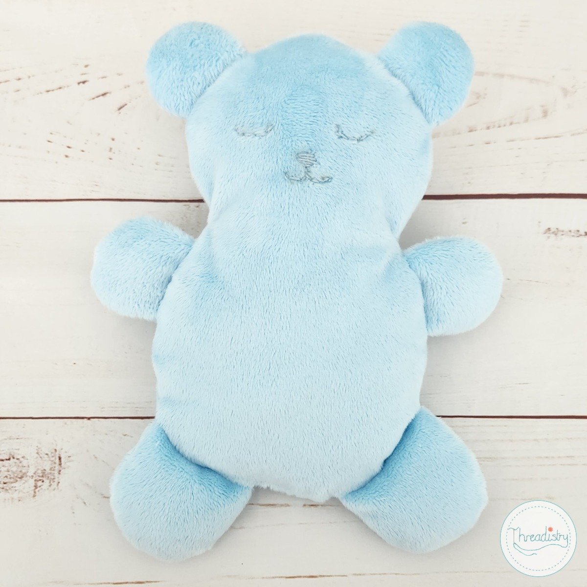 Blue flat teddy bear on a white table
