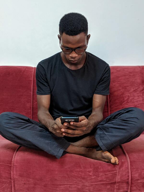 man sitting on a couch sending a text message