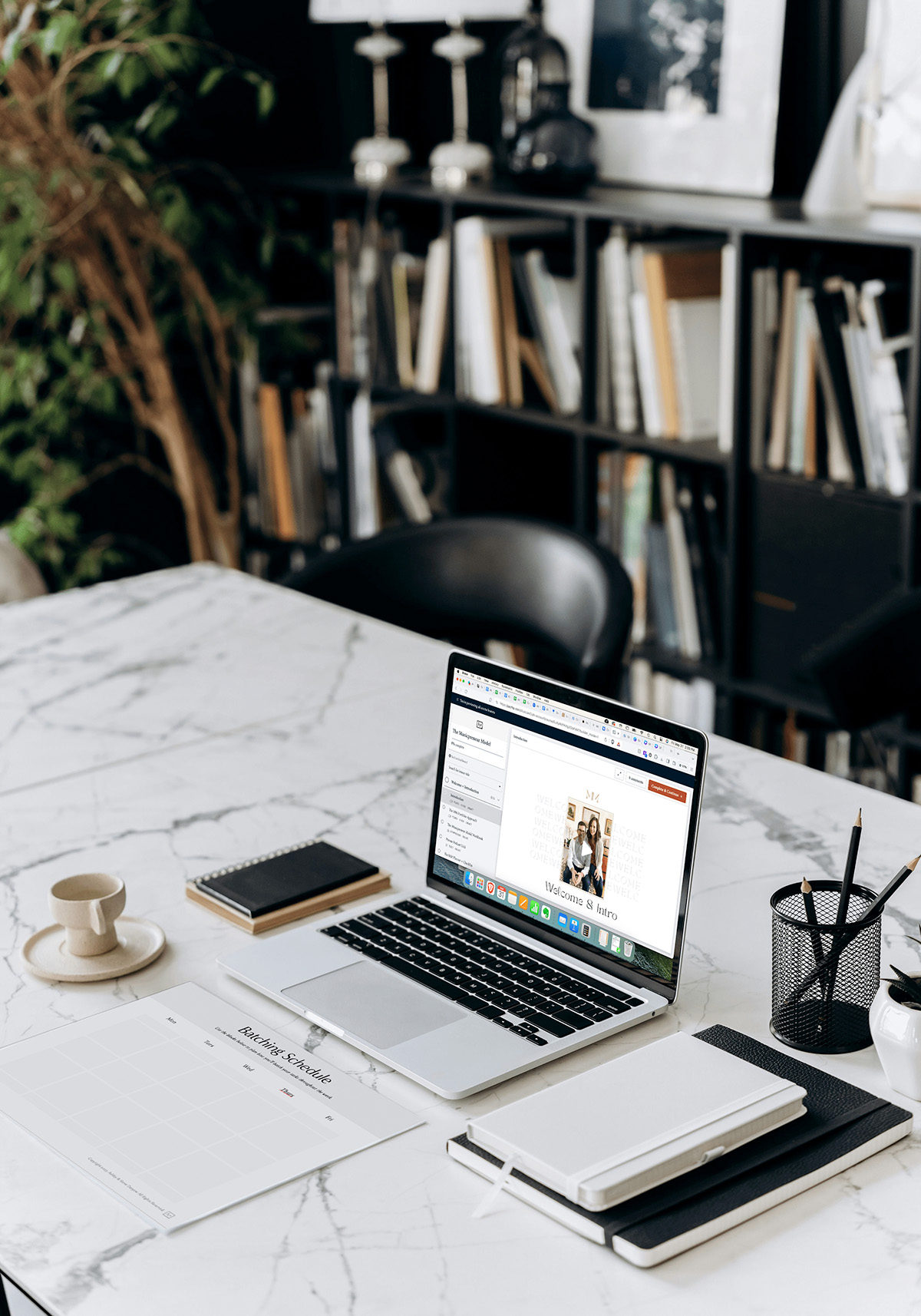 The Musicpreneur Model courses for self-employed musicians and music freelancers on laptop on marble desk with coffee, pencil cup, and notebooks