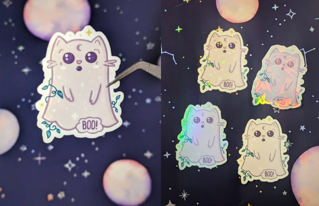 Sticker of a mischievous purple cat dressed as a ghost, saying "boo!"