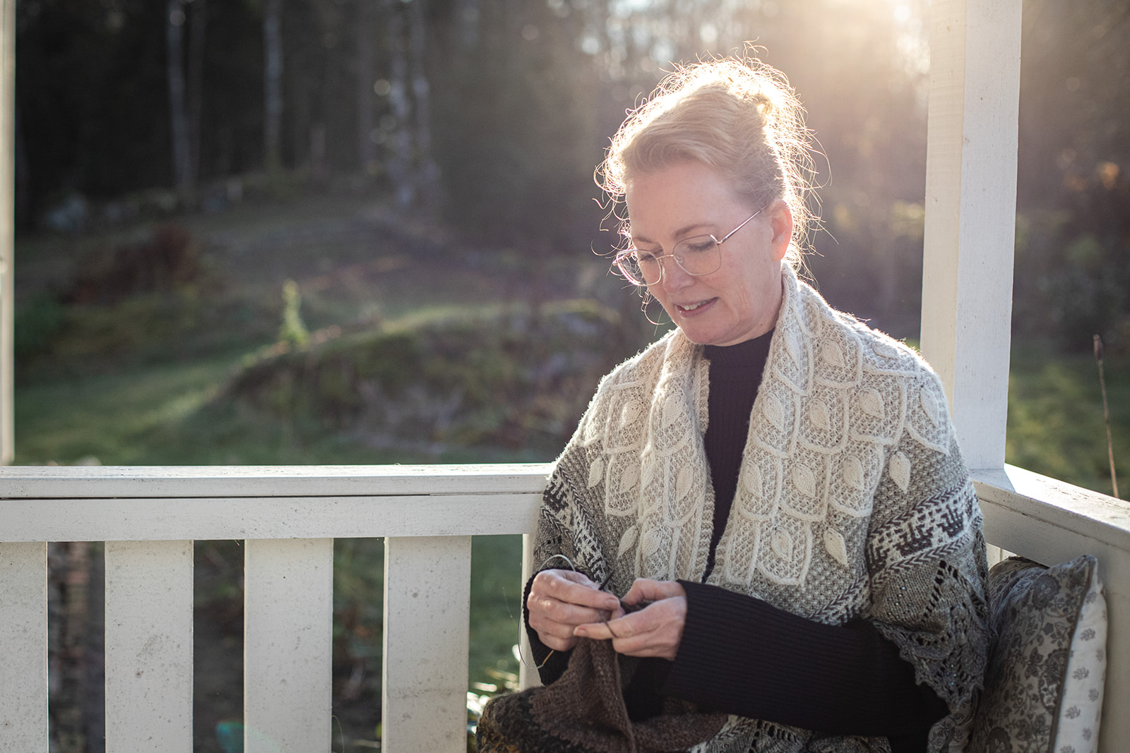 Woman knitting on a porch in the woods