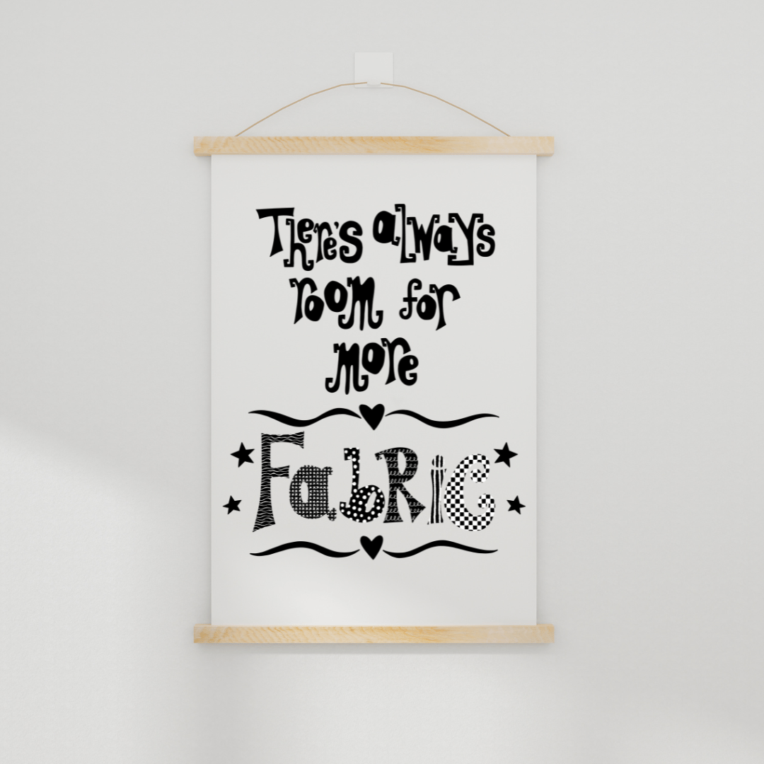 A downloadable print with a hand lettered design which says ‘there’s always room for more fabric’ in black.  Shown hanging on a wall in a simple wooden poster hanger.