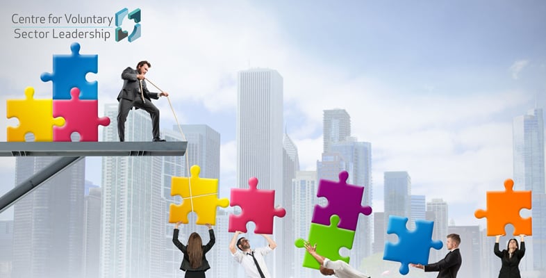 A city skyline with people assembling colourful puzzle pieces, led by a man on a metal beam