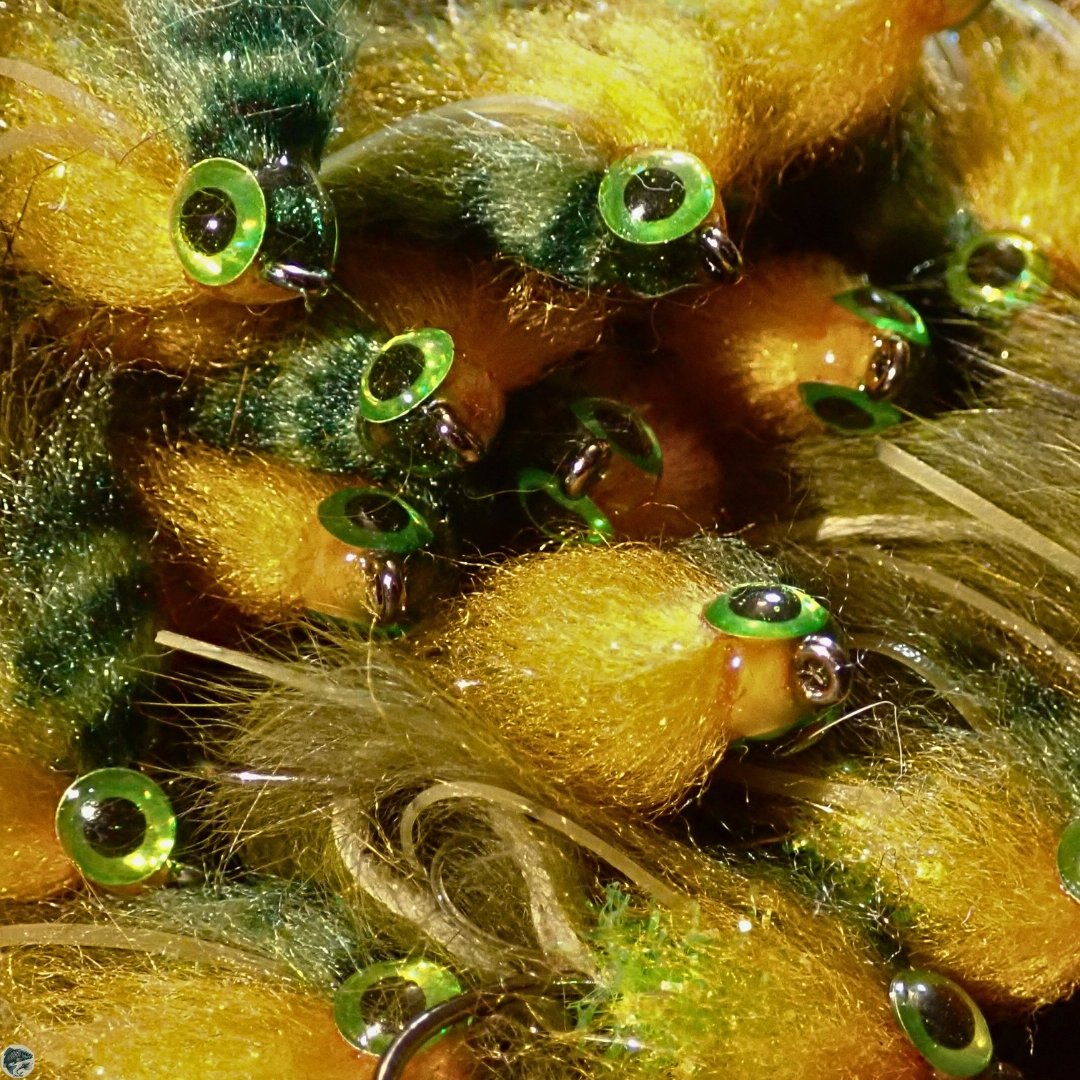 A close up of a pile of Bass Zonker Streamer flies in sunfish colors, perfect for bass fly fishing.