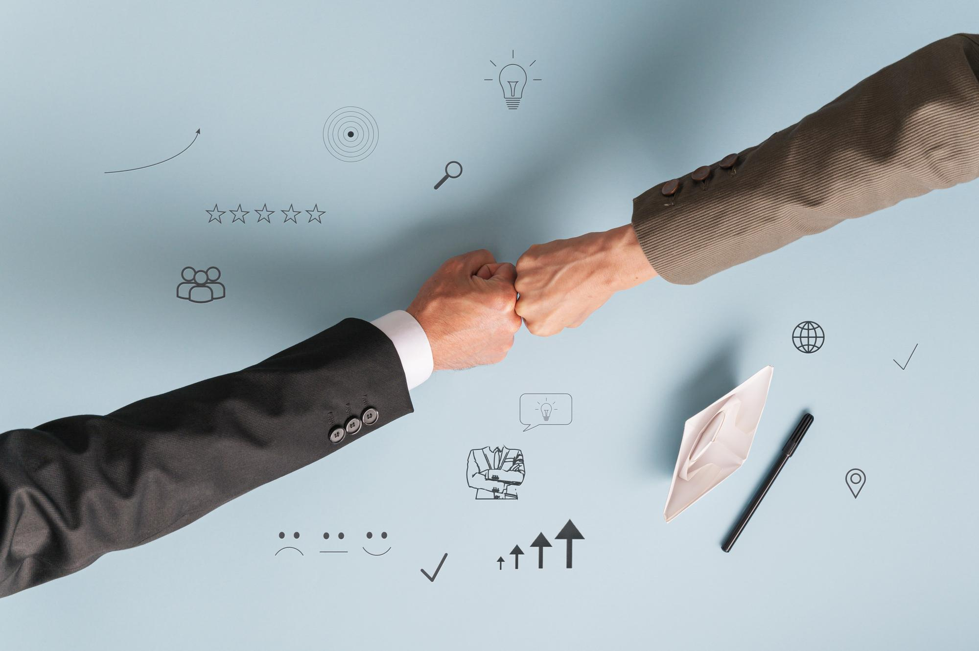 Vue de dessus de mains d'hommes d'affaires se frappant les poings au-dessus d'un tableau d'affichage sur fond bleu - concept de partenariat d'affiliation marketing