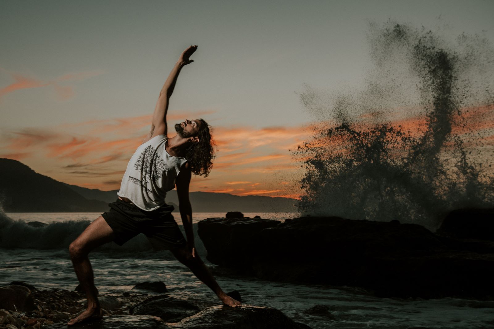 Tristan doing yoga while a wave crashes in the background