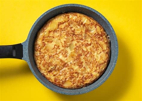 Tortilla de patata en sartén, fondo amarillo