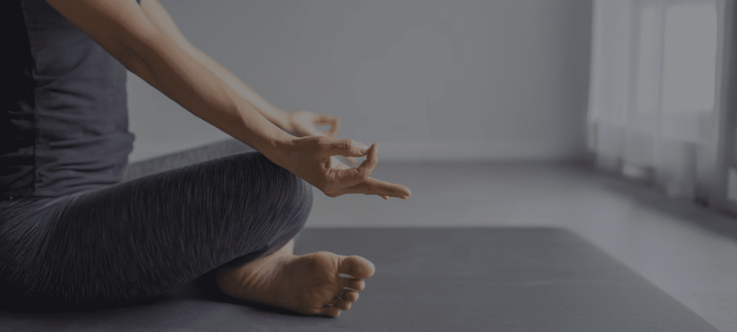 woman sitting in meditation on a mat on the floor