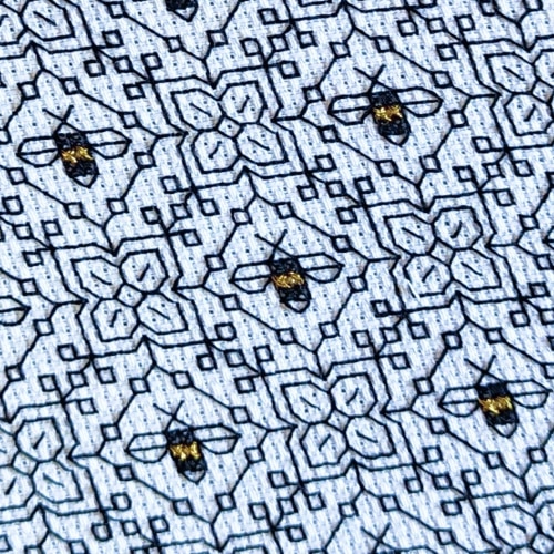 A close up of a stitched embroidery piece of small black and gold bumblebees
