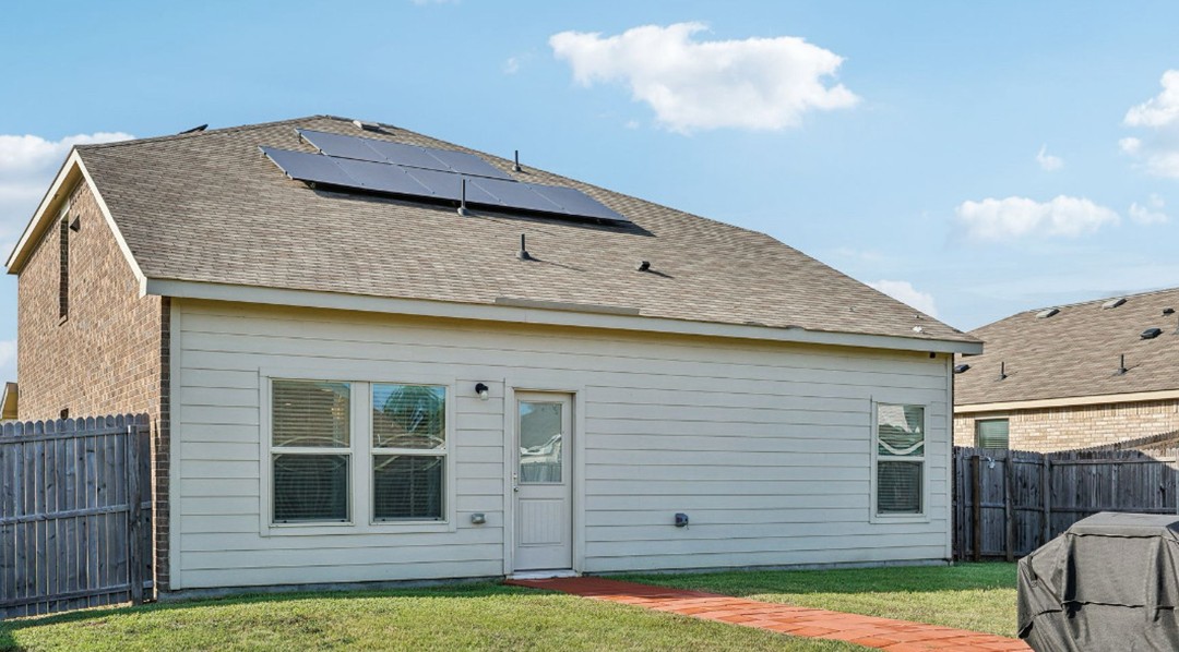 Spacious fenced backyard with a manicured lawn, small tree, and wooden privacy fence — illustrating a low-maintenance outdoor space perfect for homeowners or tenants.