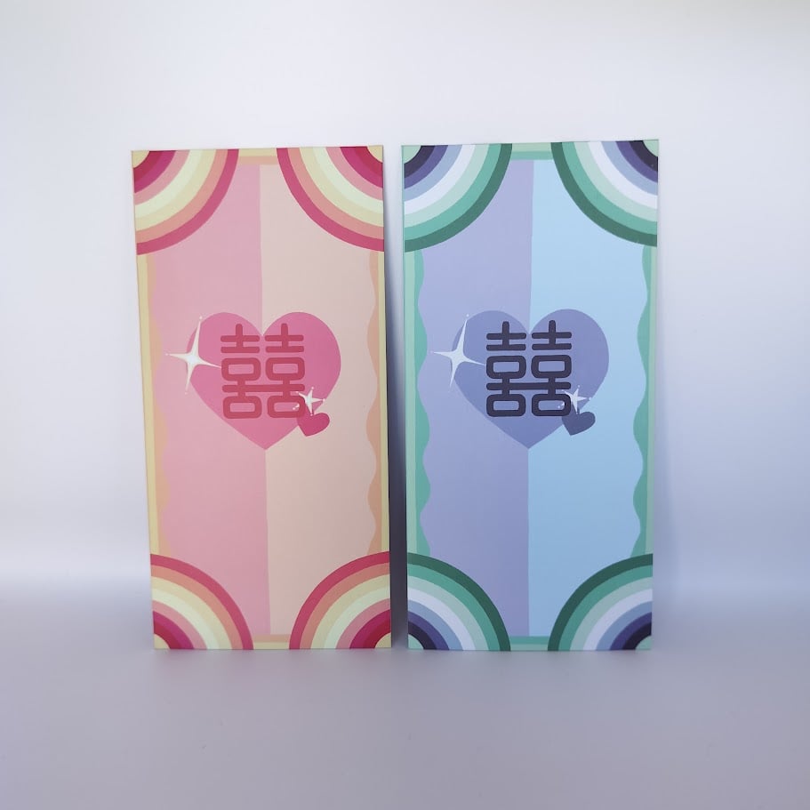 Two money envelopes side by side with rainbow arc designs - a pink and yellow striped envelope with pink heart containing Chinese double happiness characters, and a blue and green striped envelope with blue heart containing the same characters.