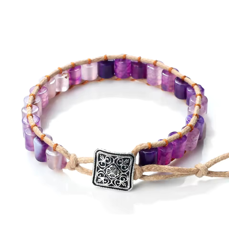 Artisan-crafted wrap bracelet featuring polished purple, lilac, and deep violet gemstone barrel beads, intricately woven onto a light brown natural cord, and secured with a decorative square antique-silver style button clasp.