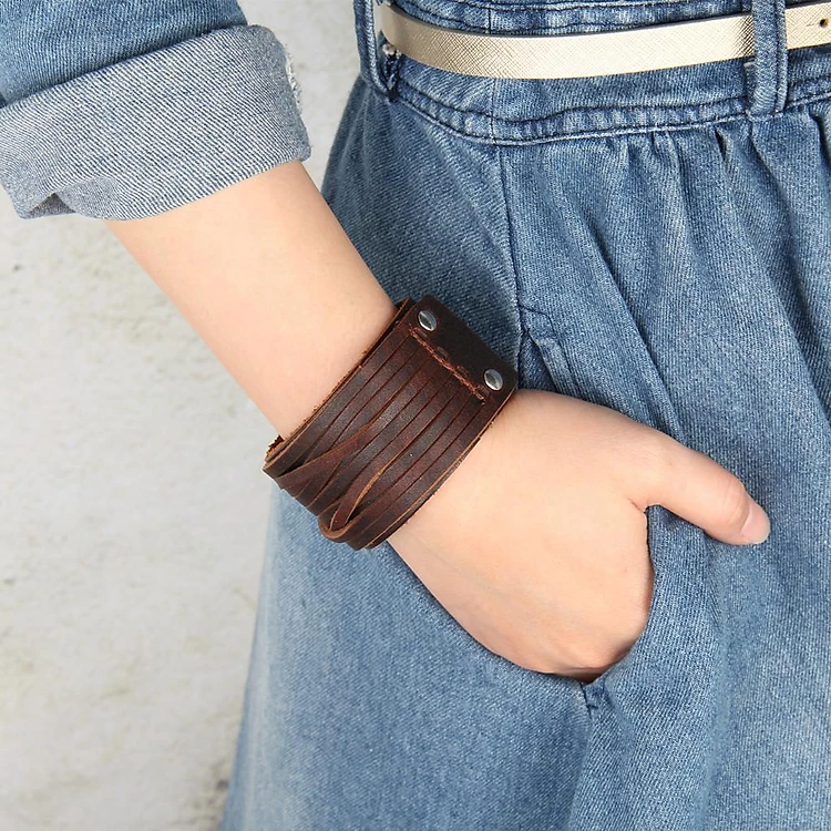 Woman wearing a dark brown Vintage Two Layers Wide Leather Cuff Bracelet (Product ID: jf86182040) on his wrist. This punk-style bangle wristband features multiple overlapping straps and is styled with a grey graphic print sleeveless top.